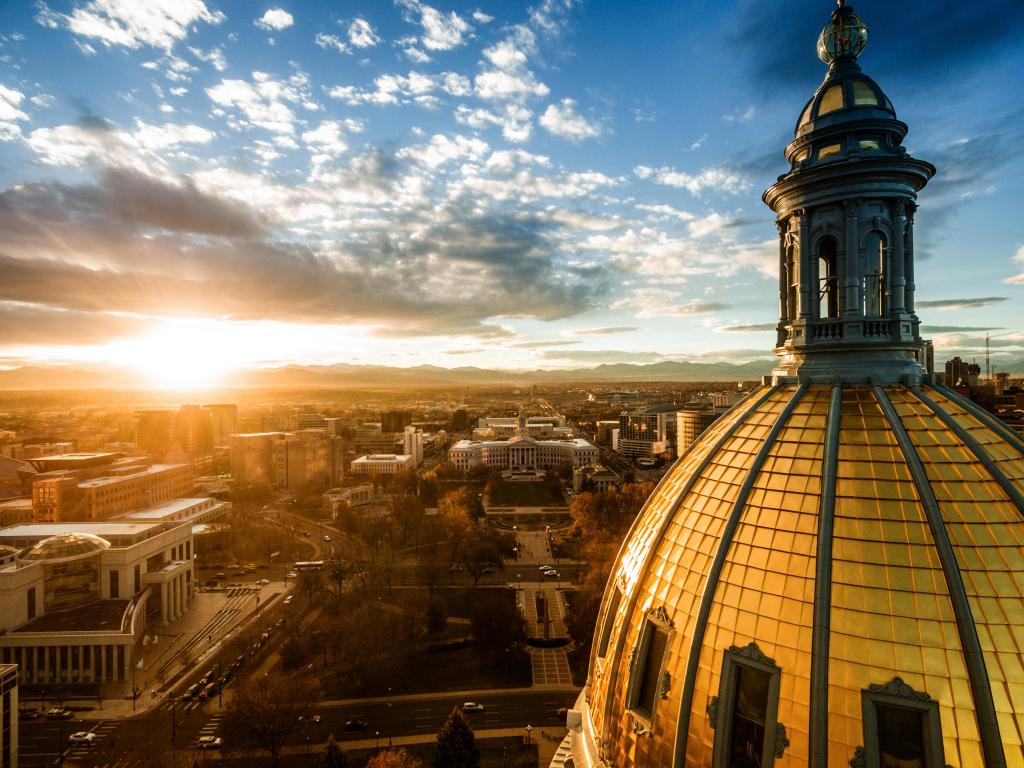 Domed roof lit up by bright sunlight with city landscape in the background