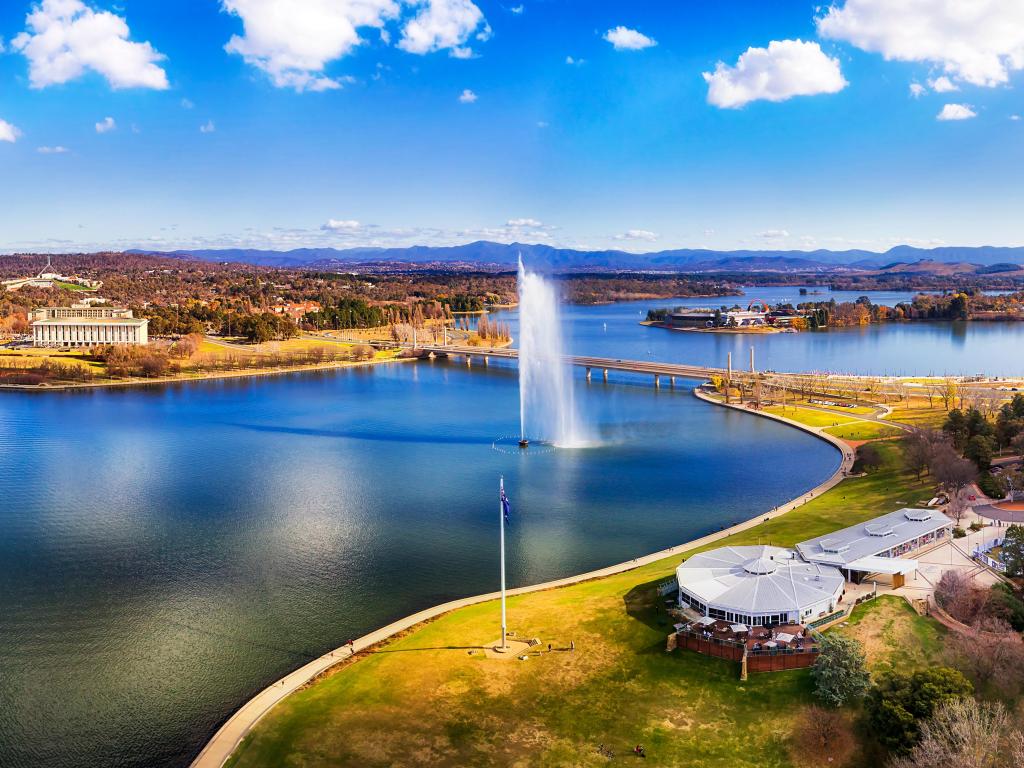 Canberra, Australia with Lake Burley Griffin surrounded by the city on a sunny day between surrounding hills.