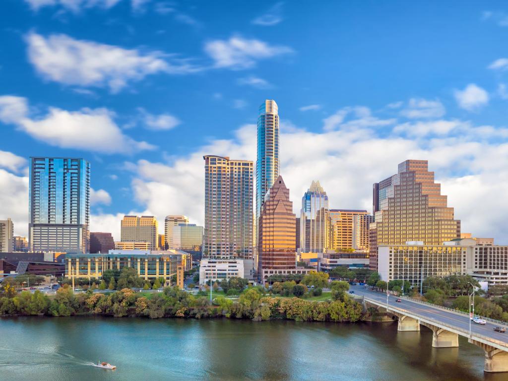 Austin, Texas in USA with the city skyscrapers in the background and water in the foreground against a blue sky. 