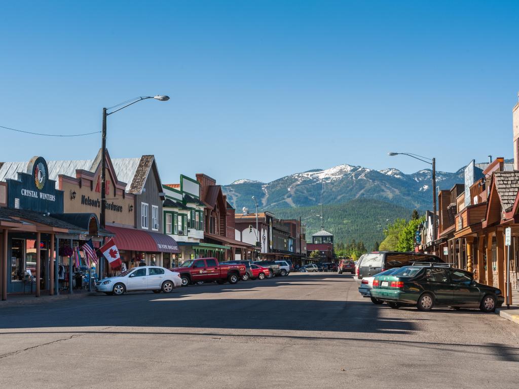 Old-fashioned and cowboy-style stores line the streets of downtown Whitefish, Montana, with mountains rising up behind on the horizon