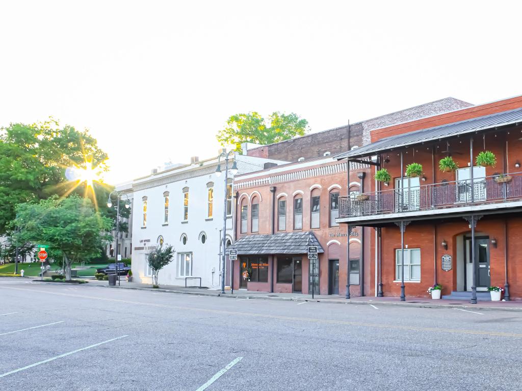 Jackson, Tennessee showing some historic buildings in the downtown city at evening sun, with a road in the foreground and some trees in the distance.