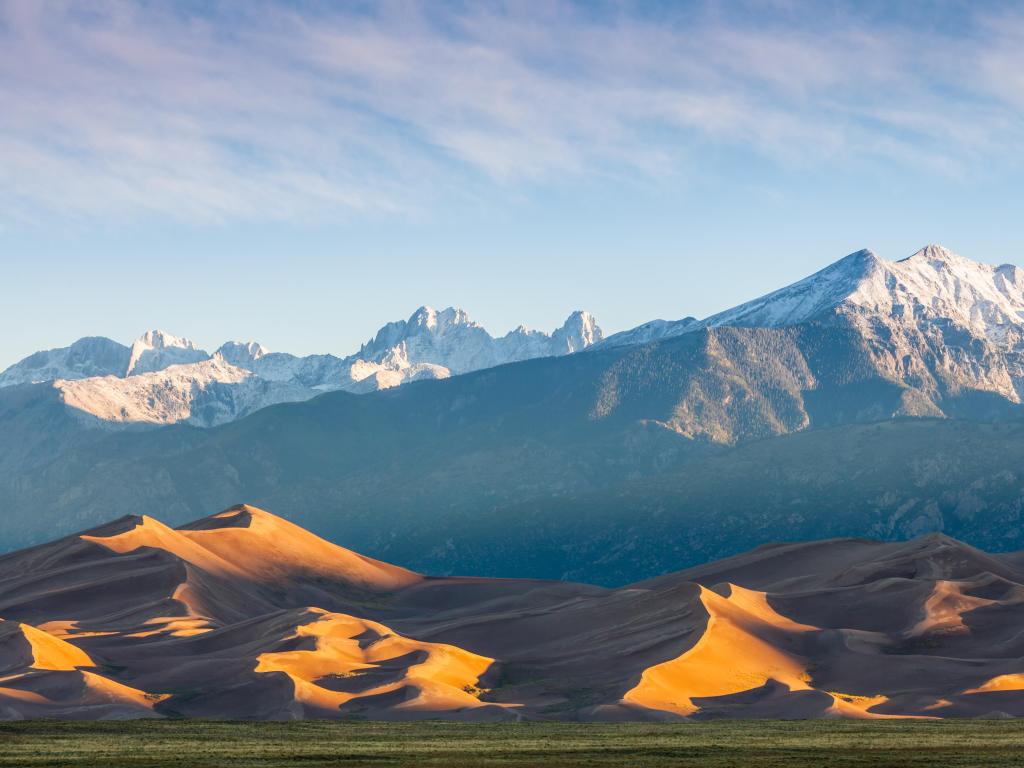 Great Sand Dunes National Park, Colorado, USA with sand dunes in the foreground and mountains in the distance on a clear day.