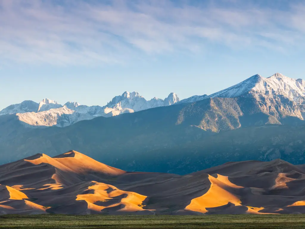 Great Sand Dunes National Park, Colorado, USA with sand dunes in the foreground and mountains in the distance on a clear day.