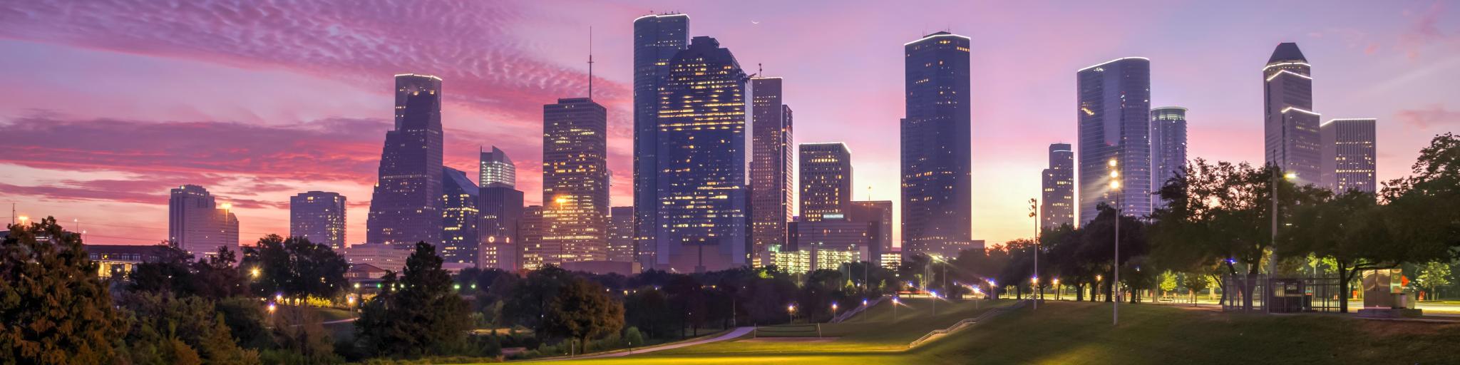 Houston, Texas at sunrise with dawn twilight with green park lawn and the skyline in the distance.