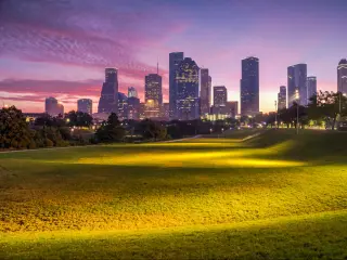 Houston, Texas at sunrise with dawn twilight with green park lawn and the skyline in the distance.