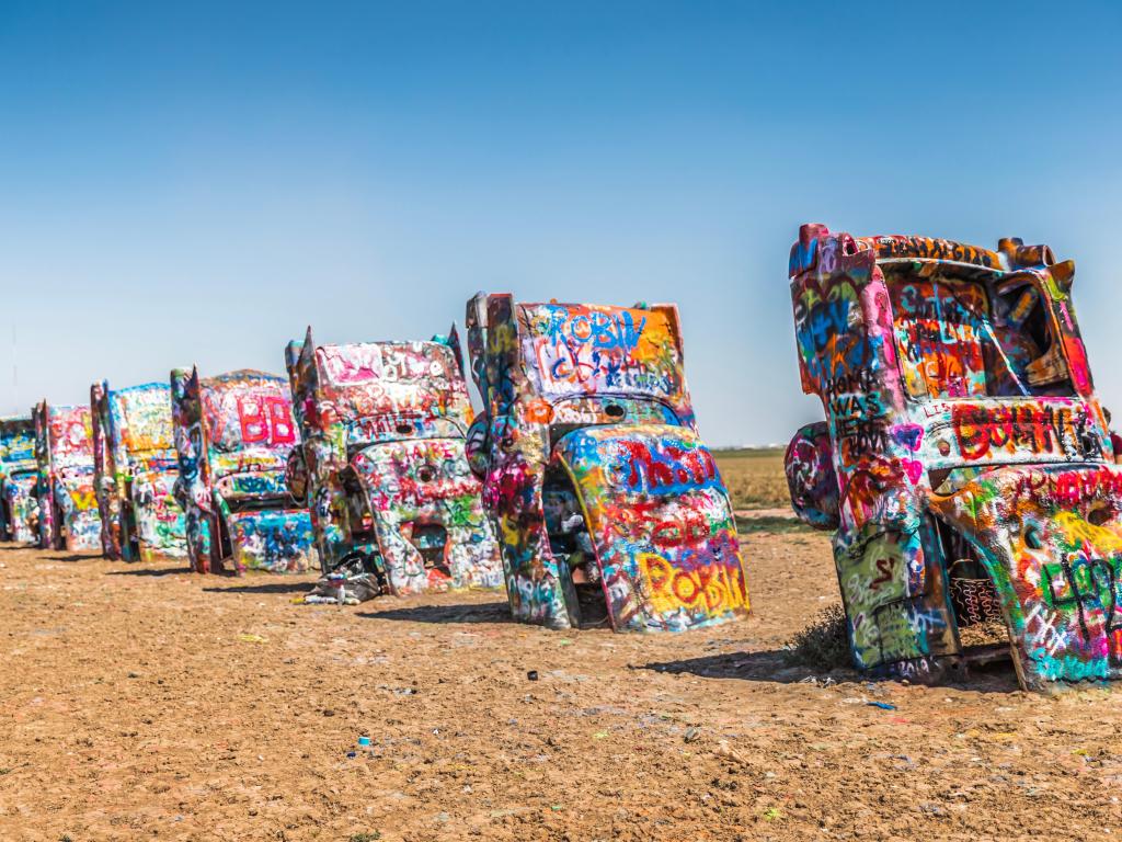 Amarillo, Texas, USA with the Cadillac Ranch, located along I-40, which is a public art sculpture of antique Cadillacs buried nose-down in a field taken on a sunny day.