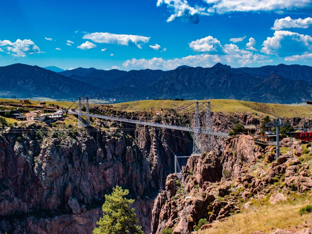 View of the Royal Gorge Bridge near Cañon City, Colorado on a sunny day, with the metal suspension bridge spanning the red canyon cliffs