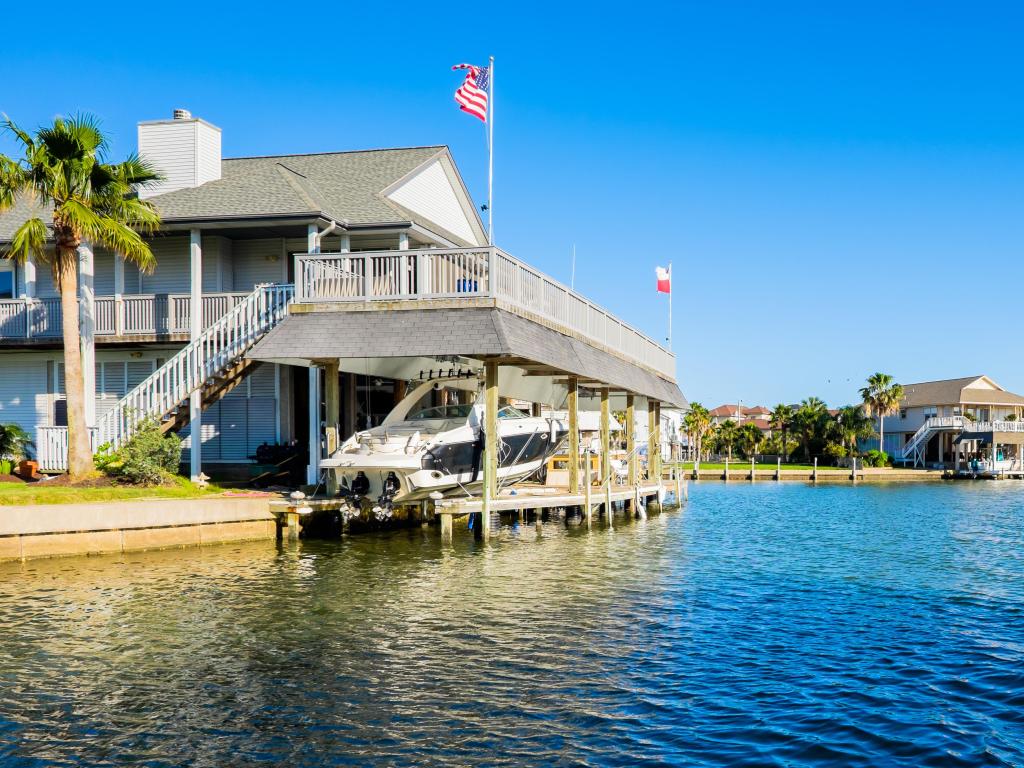 Comfortable houses situated on the waterfront with boats, green lawns, US flags and a few palm trees