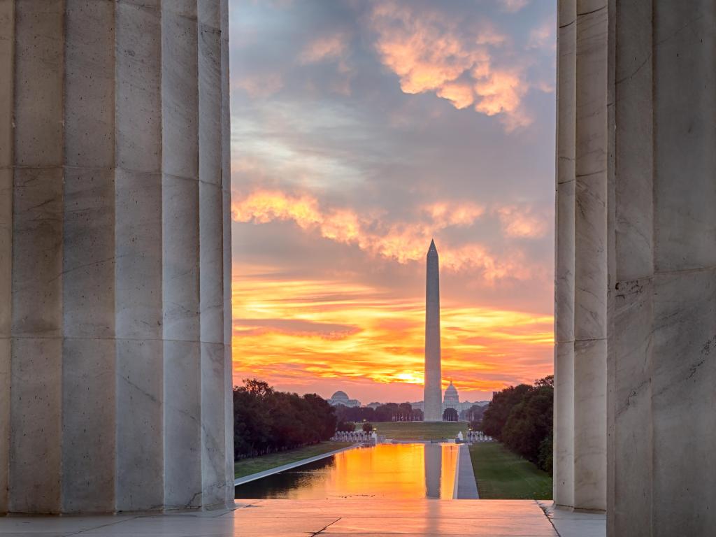 Washington Monument, Washington DC, USA with a bright red and orange sunrise at dawn reflecting the Washington Monument in new reflecting pool by Lincoln Memorial.