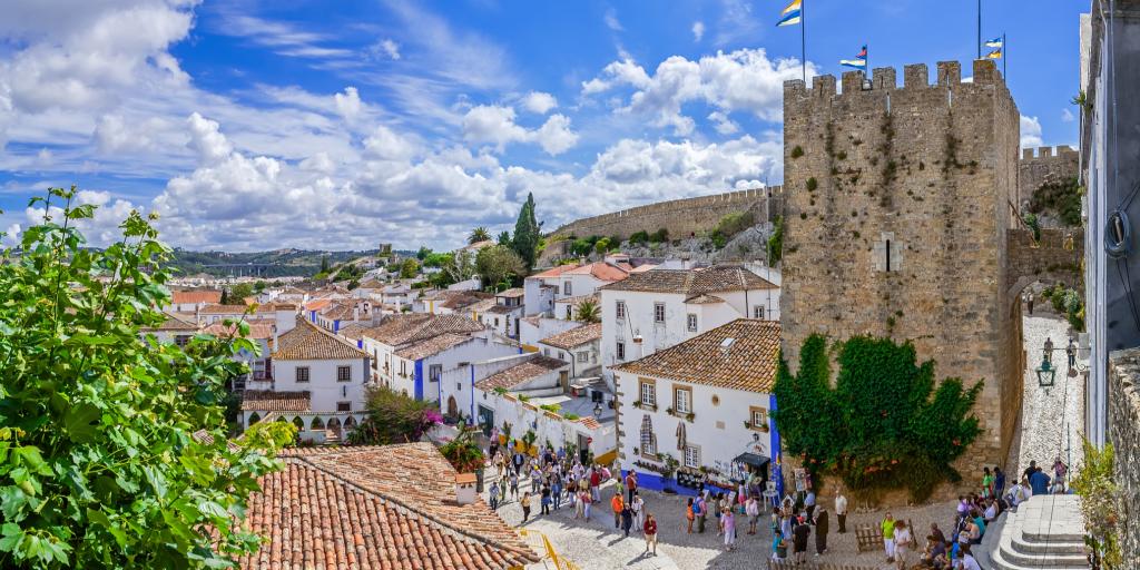 People sit on the steps in front of Obidos Castle in Portugal  on a sunny day