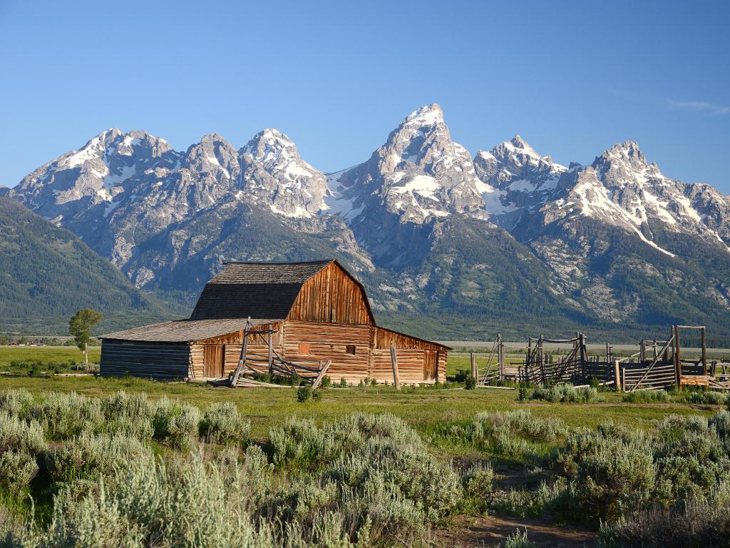 Grand Teton National Park, USA with a historic barn named Mormon Row in the foreground and the mountains in the distance.