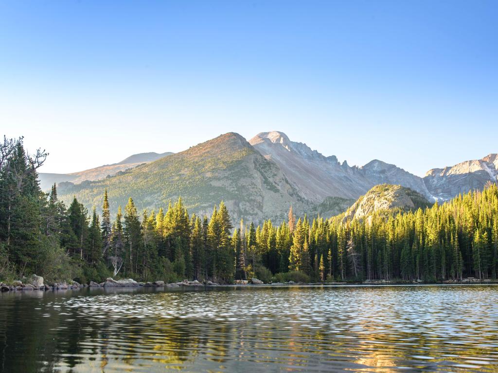 Rocky Mountain National Park, Colorado, United States taken at Bear Lake at sunrise with the mountains in the distance against a blue sky.