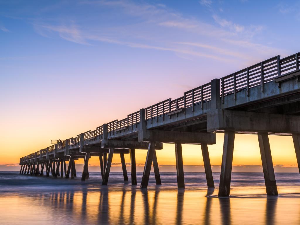 Jacksonville, Florida, USA with a beach view of the Jacksonville Pier at dawn.