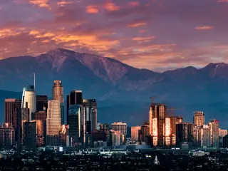Los Angeles skyline at dusk with a purple sky and mountains behind the skyscrapers
