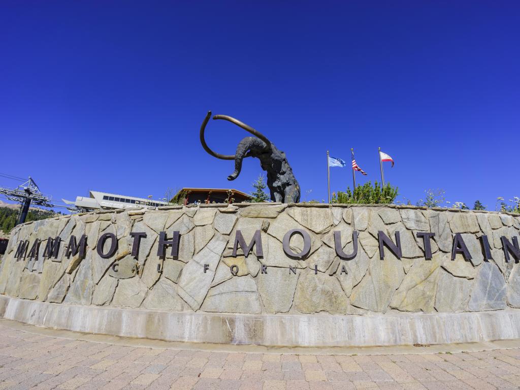 Mammoth statue and the sign for Mammoth Mountain on a bright, sunny day