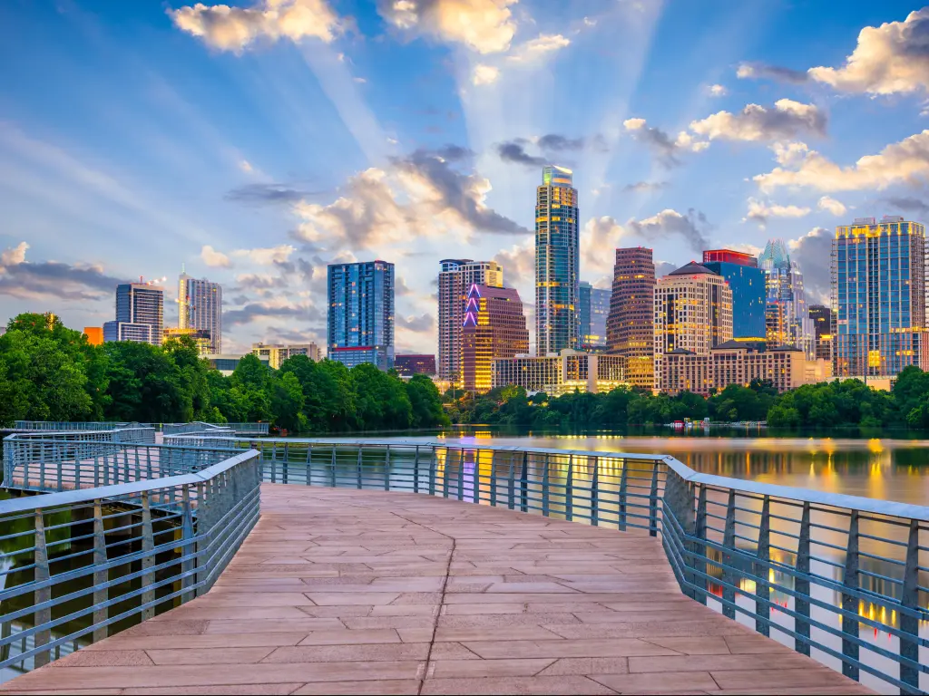 Austin, Texas, USA with a view of the downtown skyline over the Colorado River, a bridge in the foreground and a sunny sky above.