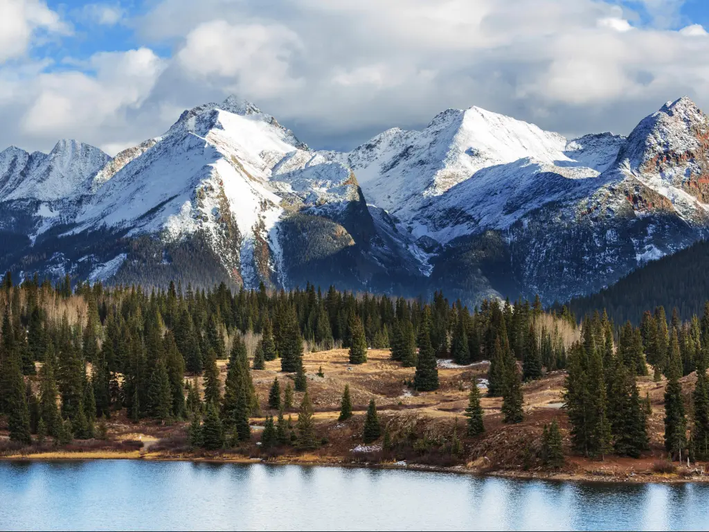 Colorado Rocky Mountains, Colorado, USA with a snow-capped mountain landscape, a lake and trees in the foreground.