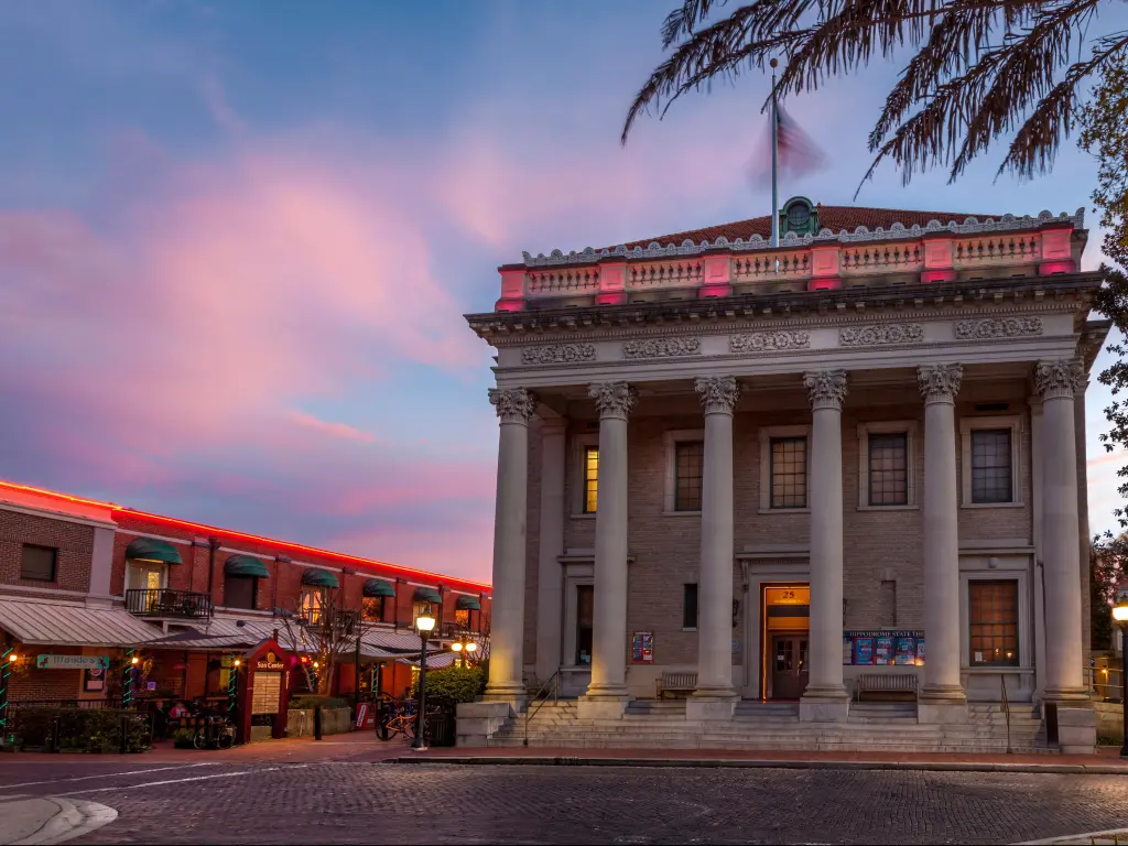 Theatre building with columns on cobbled street under sunset sky