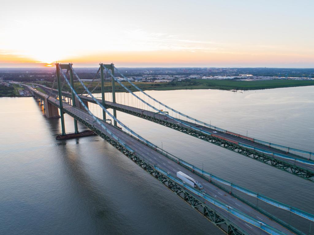 Aerial drone image of the Delaware Memorial Bridge with traffic passing along the bridge and surrounding cityscape