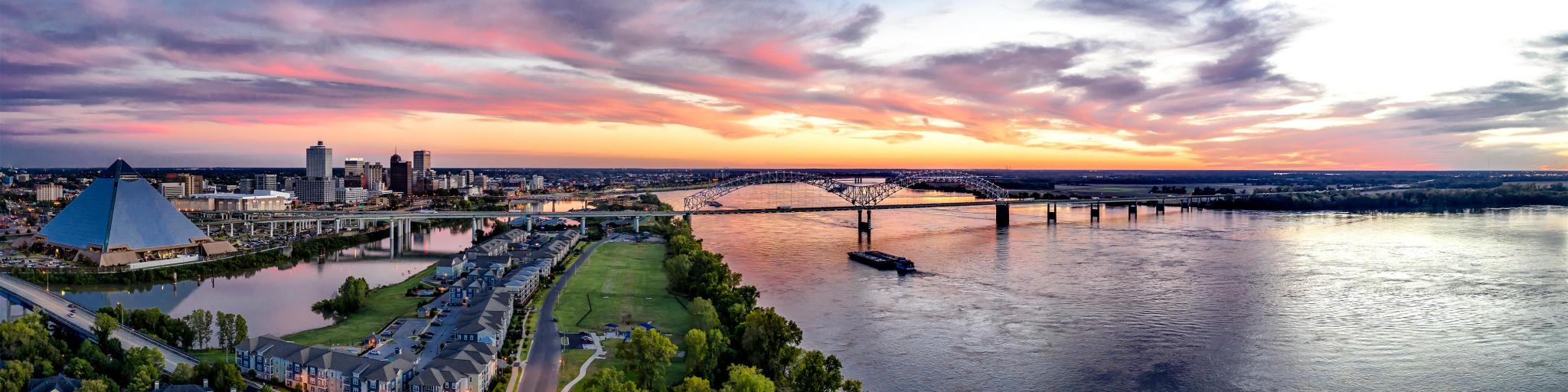Memphis, Tennessee, USA taken as an aerial panoramic view of Memphis, including Bass Pro Shops at the Pyramid, Downtown, the Wolf River Canal, and the Hernando Desoto Bridge at sunset.