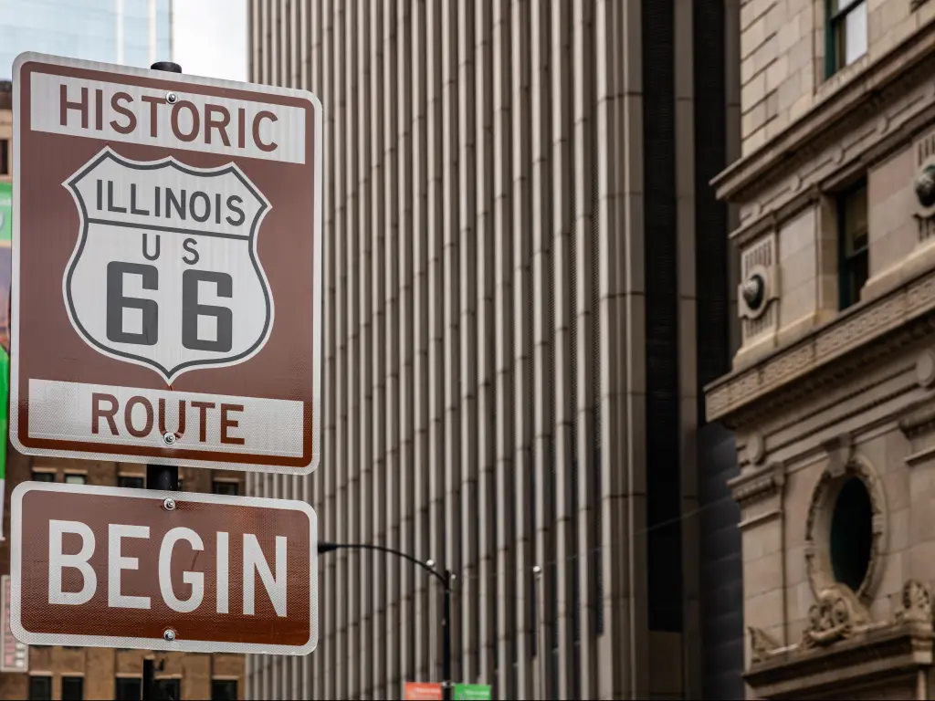 Brown "Historic Route 66 Begin" sign in downtown Chicago, Illinois, with historic buildings in the background
