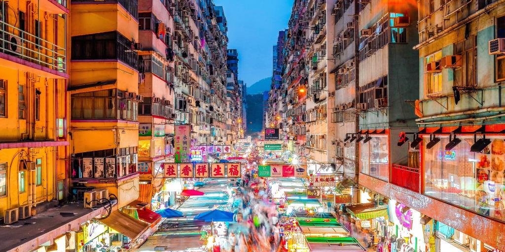 A view over the bright lights of the stalls of Mong Kok markets, Hong Kong, between the rows of high rise buildings