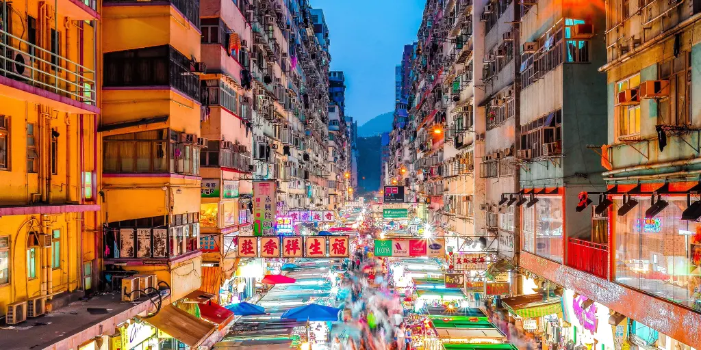 A view over the bright lights of the stalls of Mong Kok markets, Hong Kong, between the rows of high rise buildings