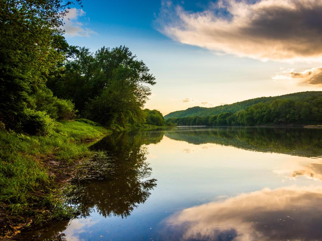 Delaware River, New Jersey, USA taken with evening reflections in the river in the foreground and surrounded by lush green land and trees either side. 