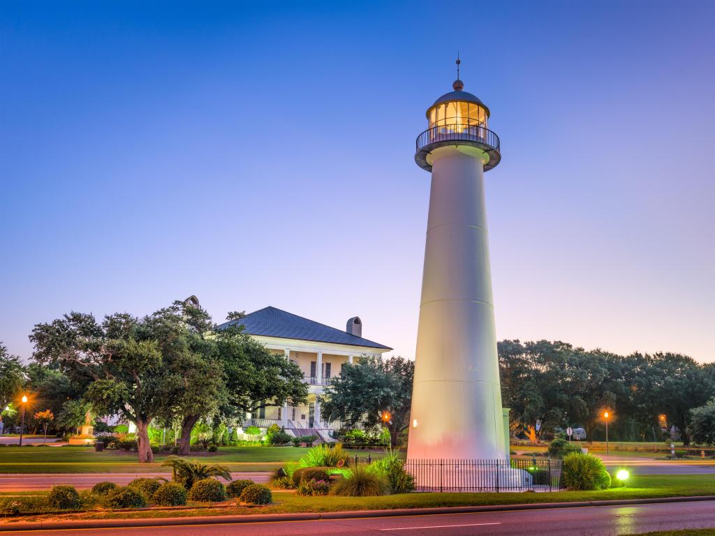 Biloxi, Mississippi, USA with its famous lighthouse taken at dusk, trees and a house in the distance.