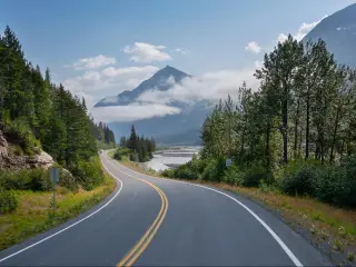 Curving highway winding through the mountains and tree in Alaska below mountains near Seward