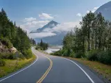 Curving highway winding through the mountains and tree in Alaska below mountains near Seward