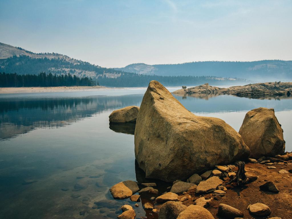 Courtright Reservoir, Sierra National Forest, California, with large rocks on the shore and shallow waters surrounded by pines on the shore