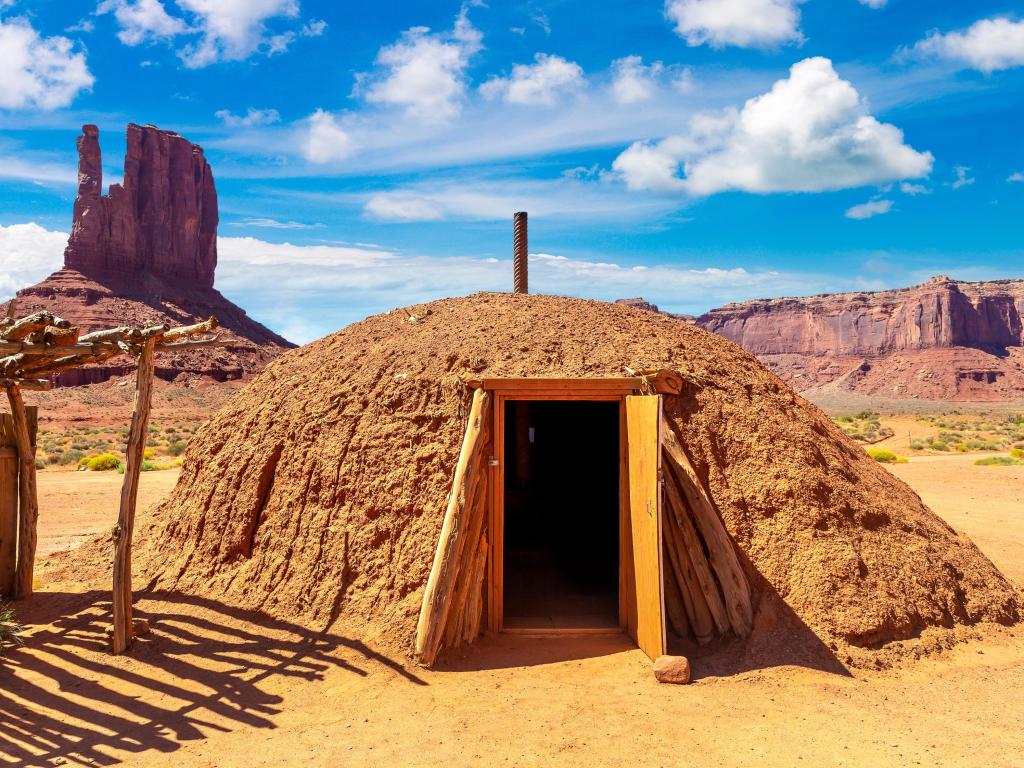 Native American hogans in Navajo Nation Reservation at Monument Valley, surrounded by desert landscape and blue skies, Arizona, USA