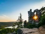 Devils Lake, Wisconsin, USA at sunset with rocks in the foreground and the lake and trees in the distance. 