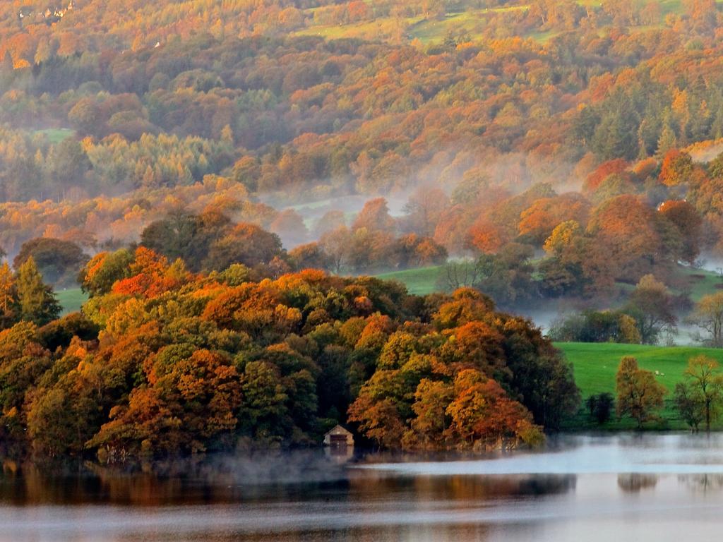 A morning mist rolls over the colourful trees and glittering Lake Windermere in the Lake District