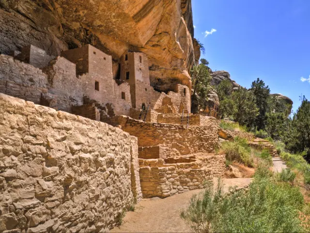 Historic carved buildings at Cliff Palace in Mesa Verde National Park, with blue sky above