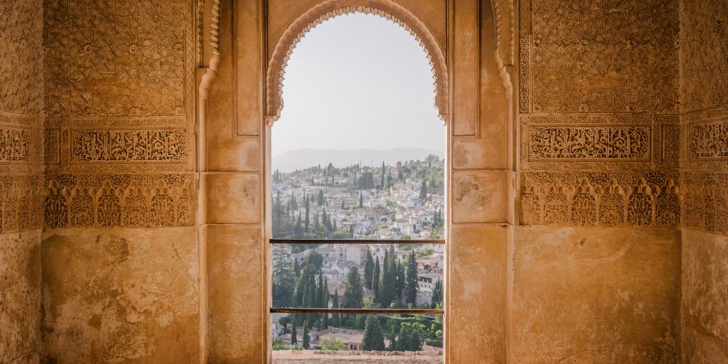 The rooftops and trees of Granada as seen through a Moorish door in the Alhambra fortress