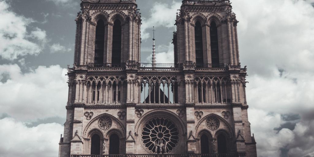 The Notre Dame de Paris towers over the city on a cloudy day