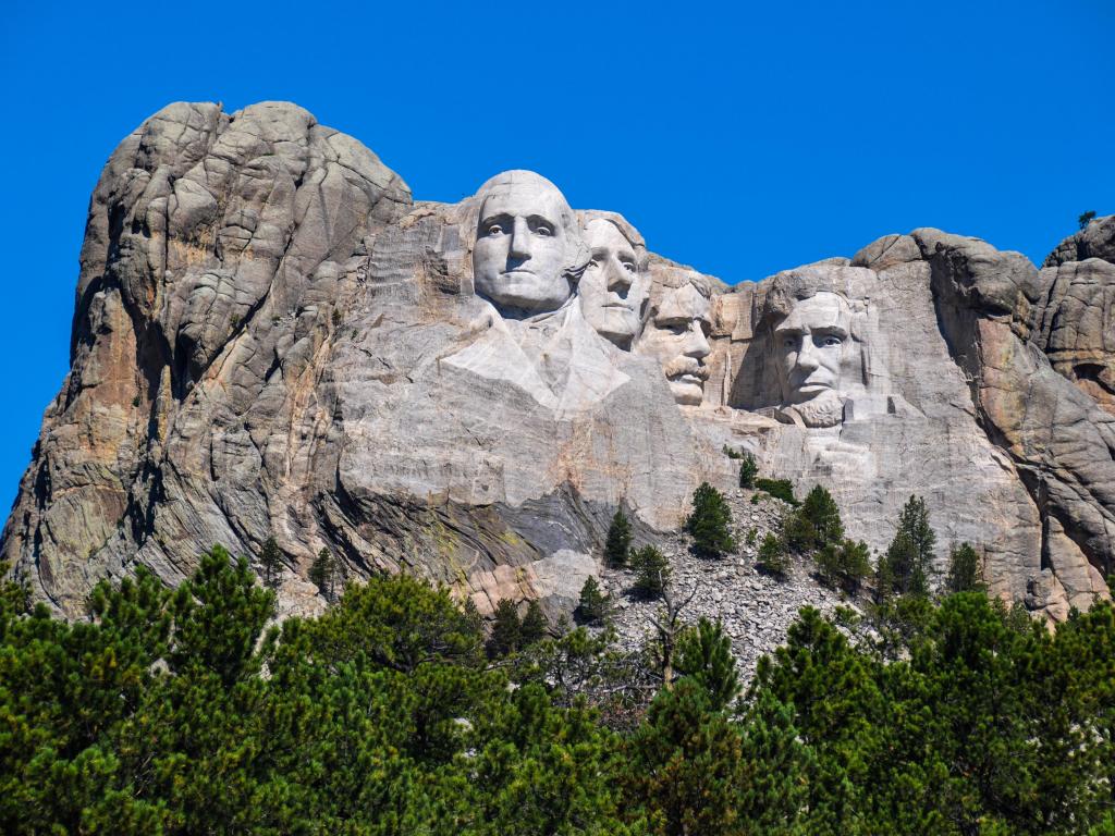 Wide view of famous US Presidents on Mount Rushmore National Monument, against blue skies, South Dakota