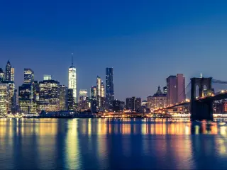 Manhattan, NYC, USA taken at night with the city skyline in the distance and the river reflecting the lights on the buildings. 