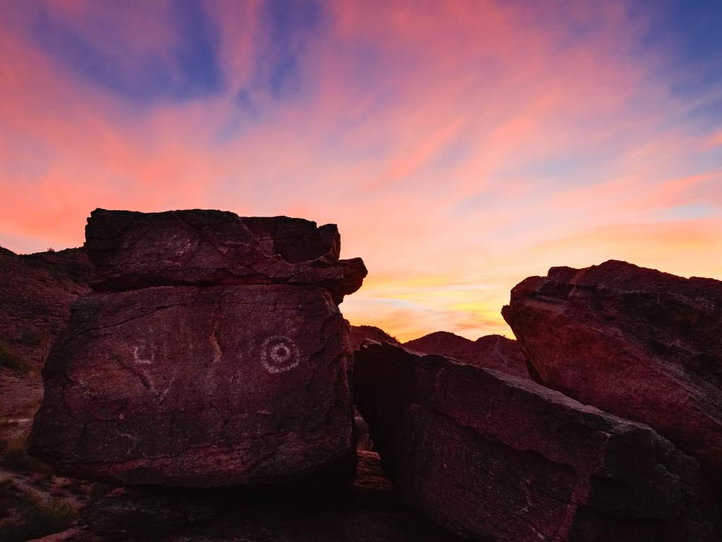Petroglyph National Monument, Albuquerque, USA with Hohokam rock art/petroglyphs in the foreground at sunset against a sunning sky.