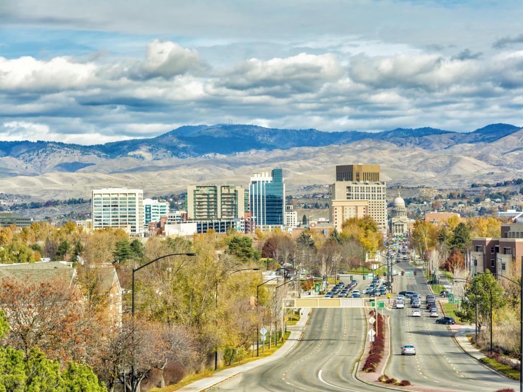 Boise, Idaho, USA with a street leading to the capital building in fall, mountains in the distance and a cloudy sky.