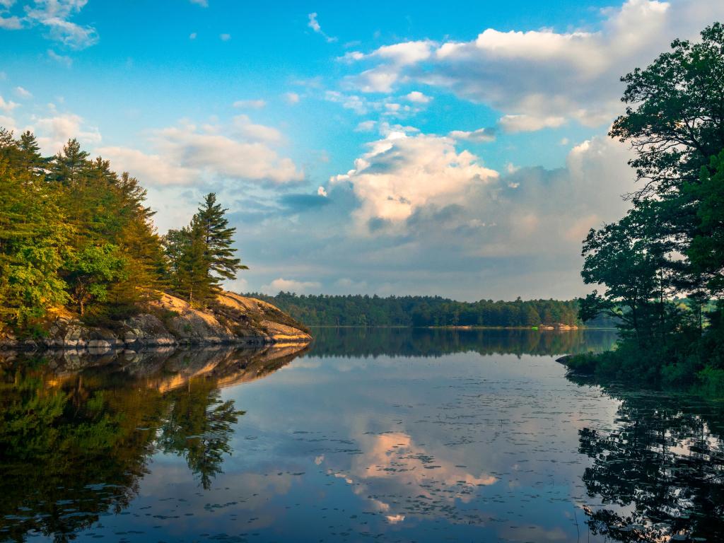 Lake Ontario, Ontario, Canada with beautiful cloud formations over the lake in Canada, surrounded by rock cliffs and forest trees. 