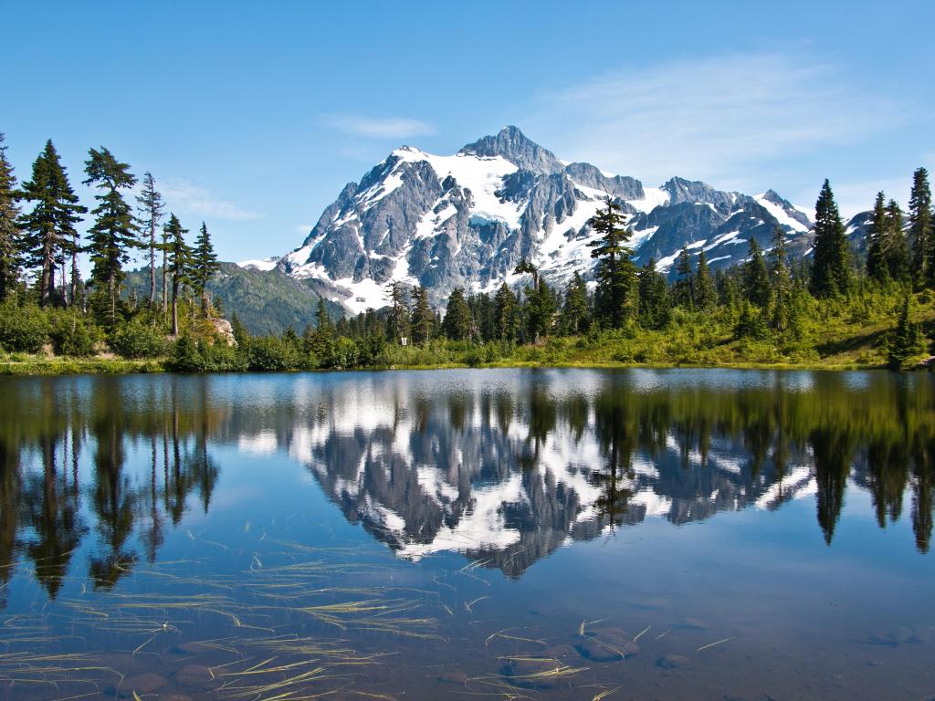 Mt. Baker-Snoqualmie National Forest, USA with a view from Mt. Shuksan and Picture Lake in the foreground, trees and the snow-capped mountain in the distance taken on a clear sunny day.