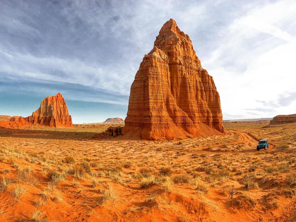 Red rock landscape with a big, pointy rock formation rising into the sky