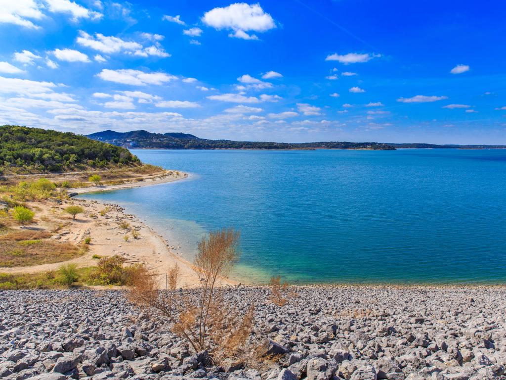 Canyon Lake, Texas, USA with pebbles in the foreground and a sandy beach in the distance.