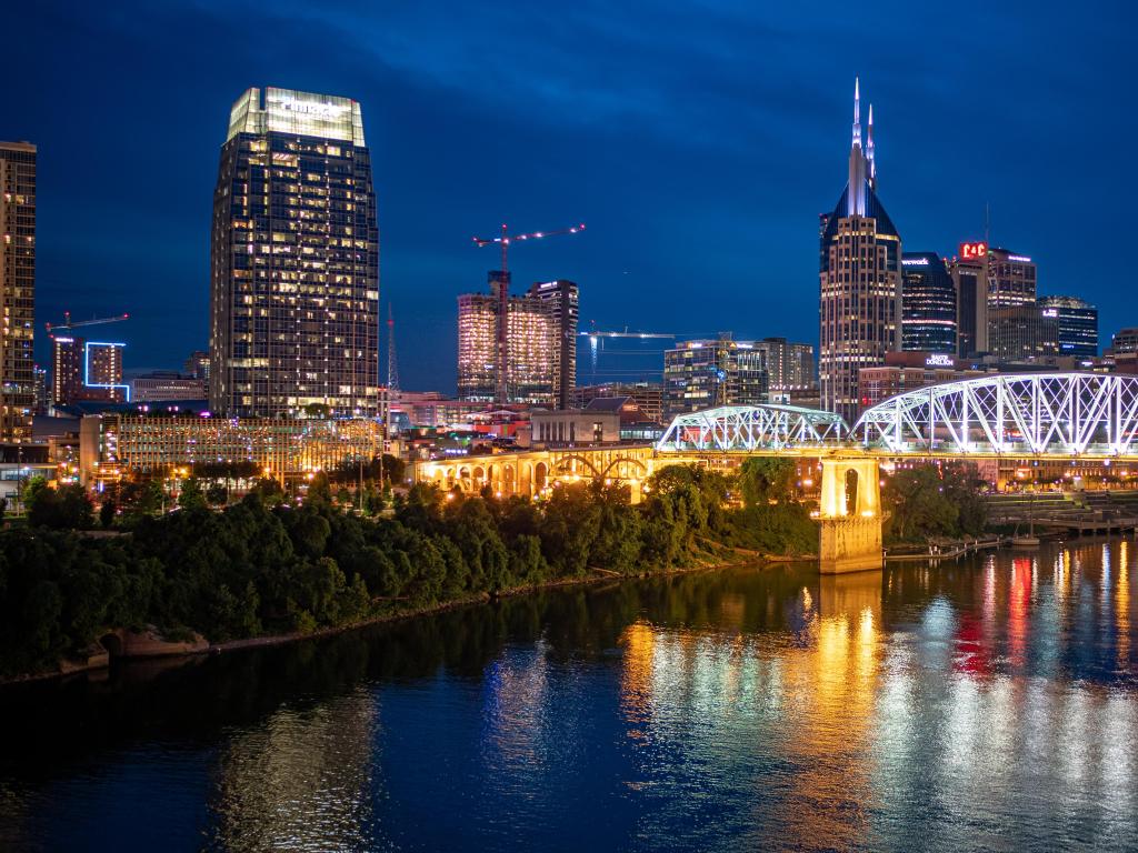 Nashville, Tennessee, USA with the skyline over the river and bridge at night.