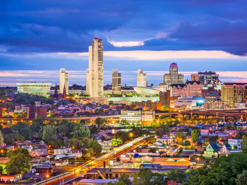 Albany, New York, USA city skyline at twilight, with dramatic clouds in the sky and the city lights on. 