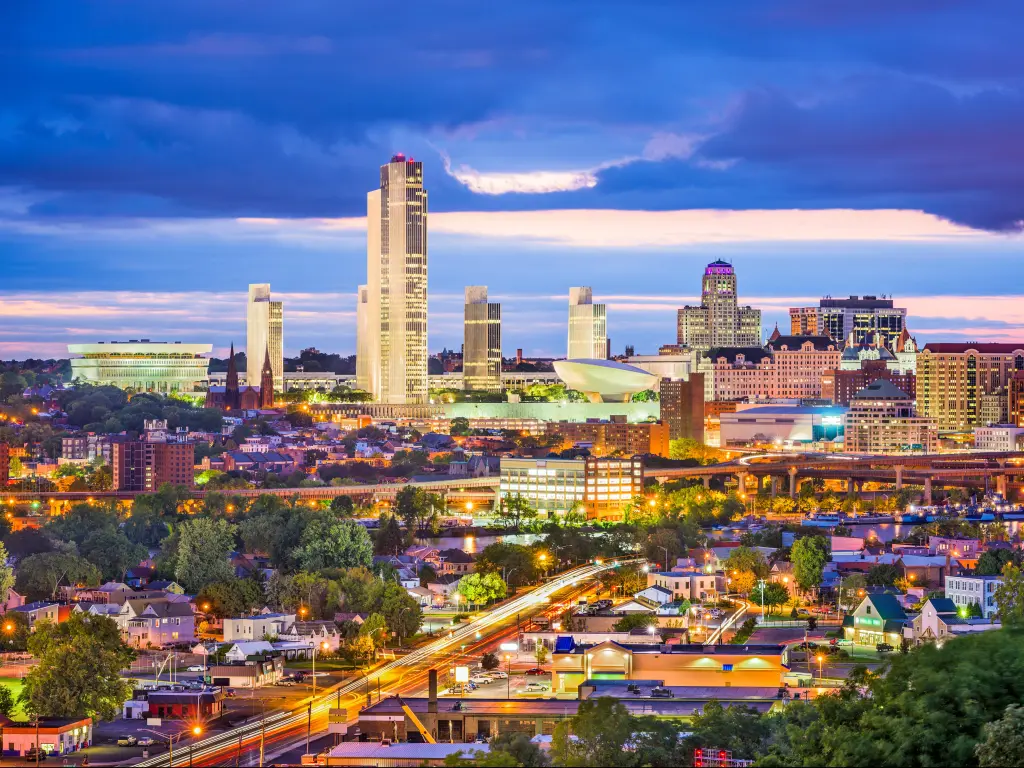 Albany, New York, USA city skyline at twilight, with dramatic clouds in the sky and the city lights on. 