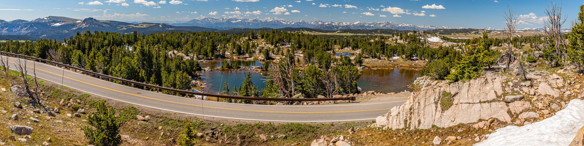 Stunning views over Beartooth Highway, with panoramic views of winding road in forefront and lush landscape and hills behind 